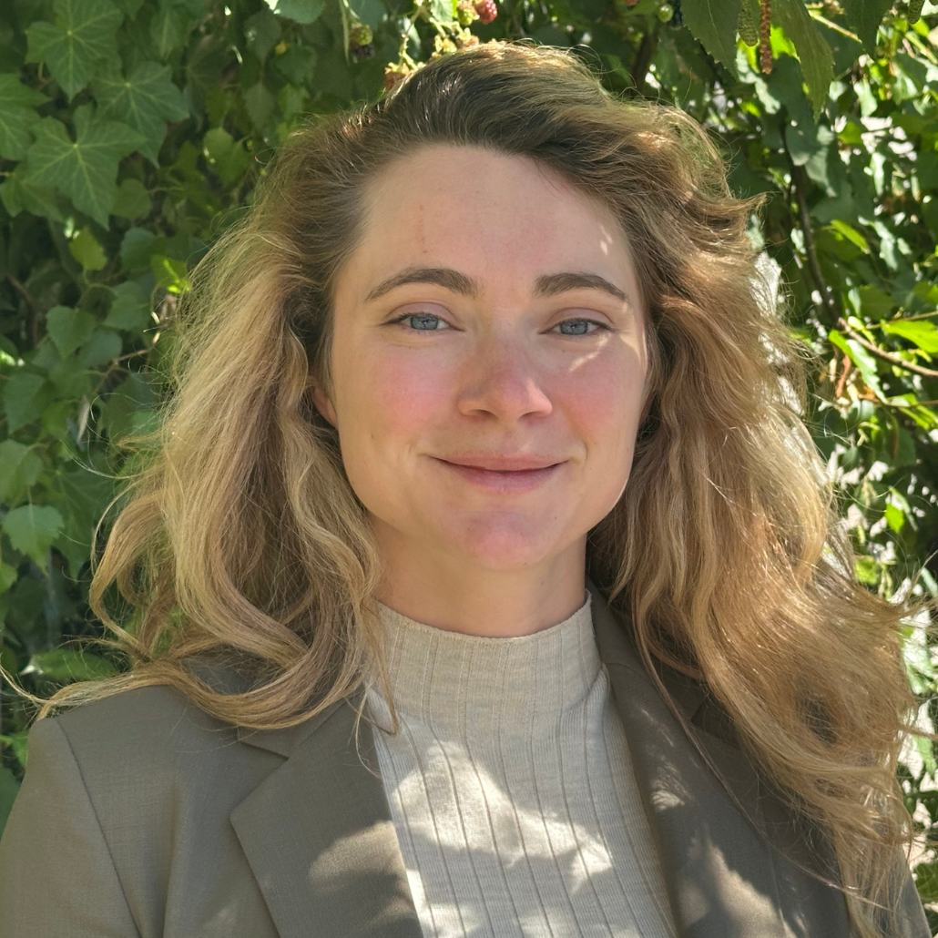 A woman in a blazer standing in front of a tree