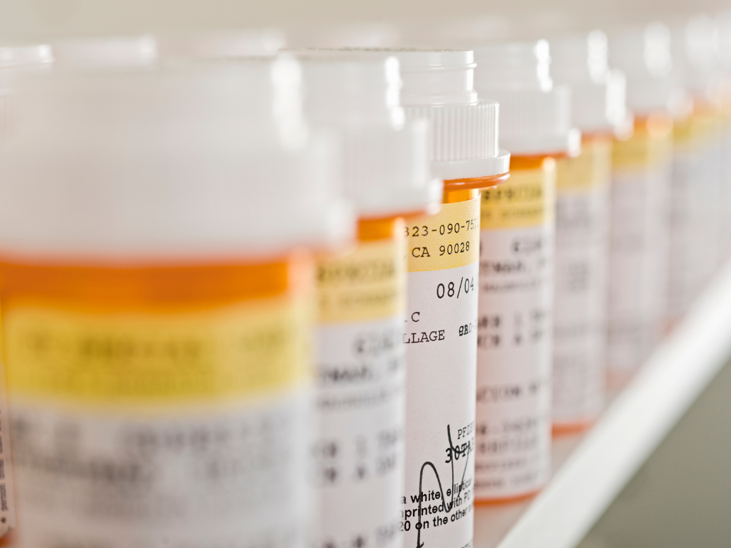 Bottles of prescription medication lined up on a shelf.