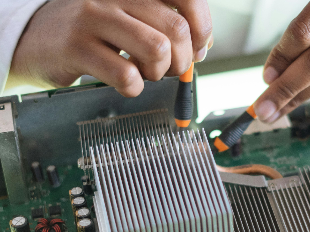 Close-up of hands repairing electronic equipment with small tools.