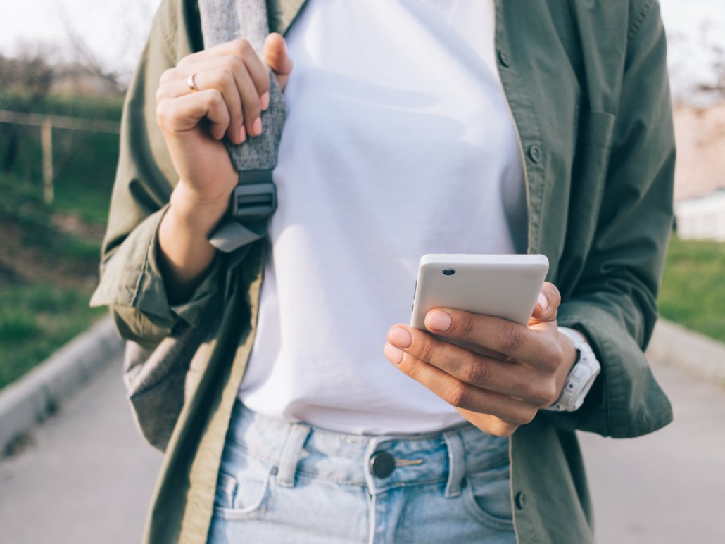 Person using a smartphone while walking, dressed casually.