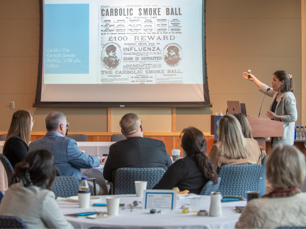 Nadia Dahab speaks to a group with a historical advertisement on the screen at OCJ’s first CLE.