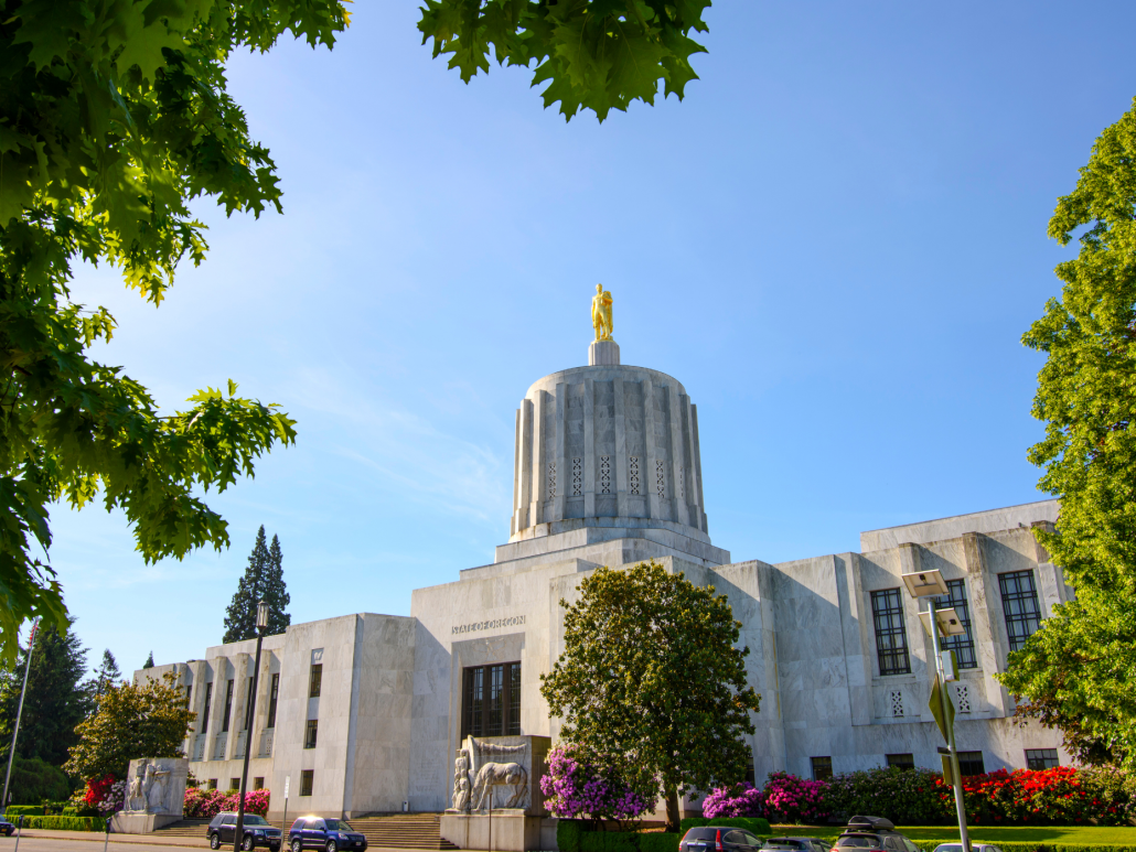 Oregon State Capitol building framed by green trees.