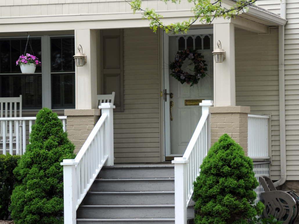 The front porch and steps of a modest beige and white home.  