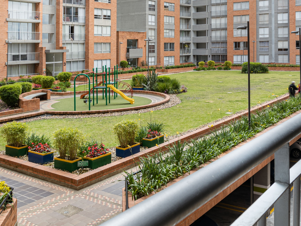 A modern apartment complex courtyard with a playground and greenery.