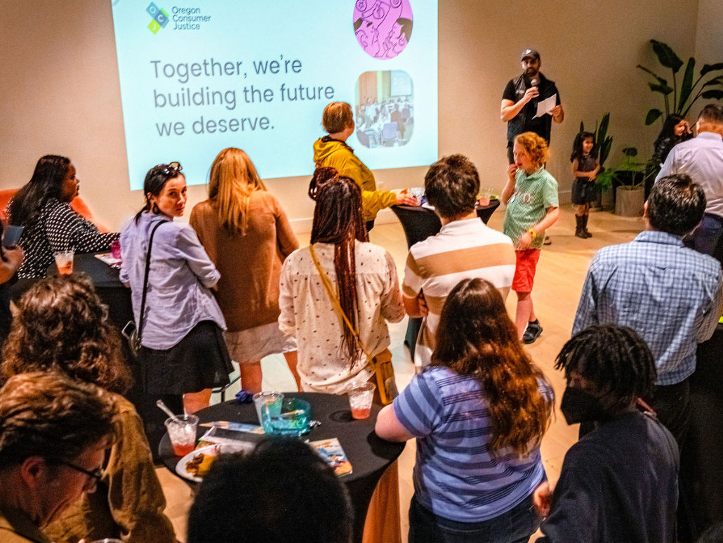 Group of people at an event with the OCJ logo and writing on a screen that reads “Building the future we deserve.”