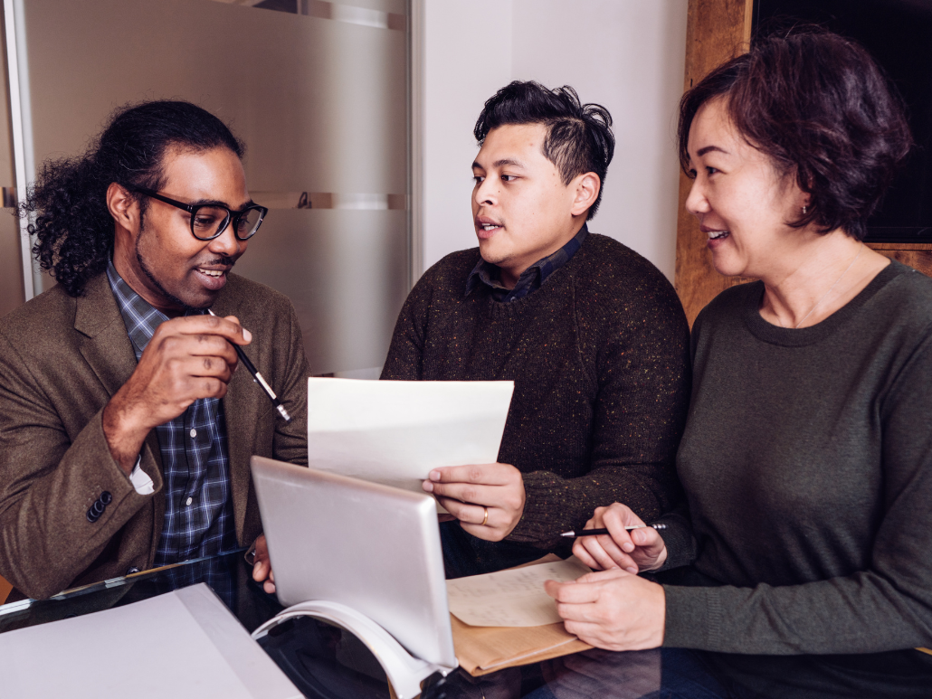 Three people sitting at a table, discussing documents.