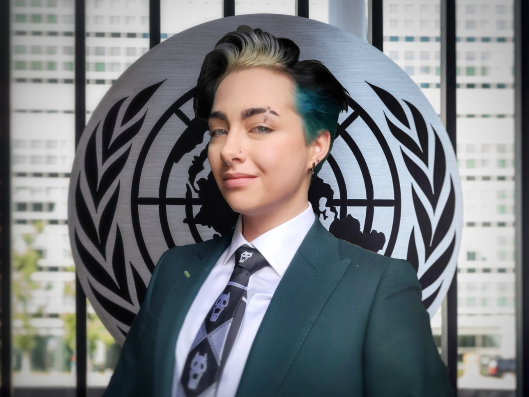 Portrait of Felix standing in front of a United Nations emblem.