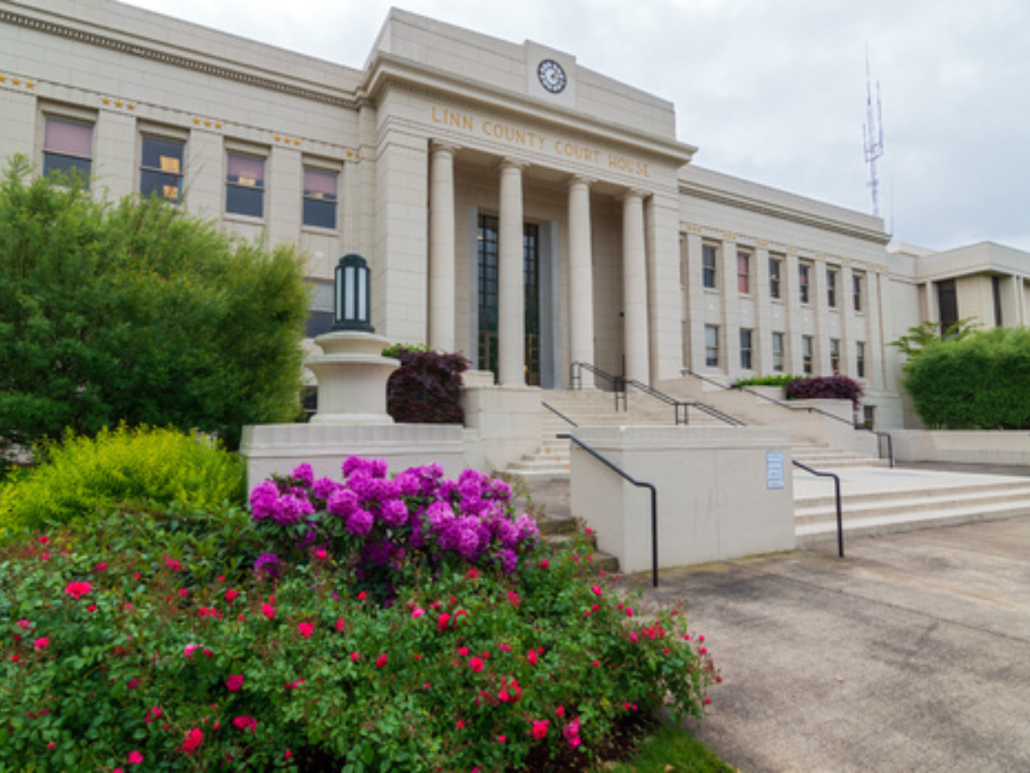 Image of the front steps of the Linn County Courthouse, surrounded by flowers in built-in planters. 