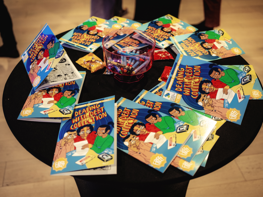 Copies of the comic books titled "Dealing with Debt Collection" and crayons on a table.