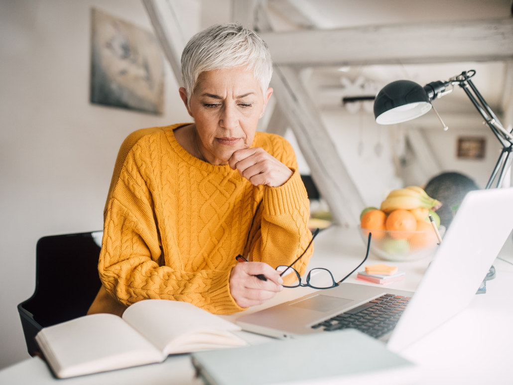 A woman sitting at a desk looking seriously at papers.