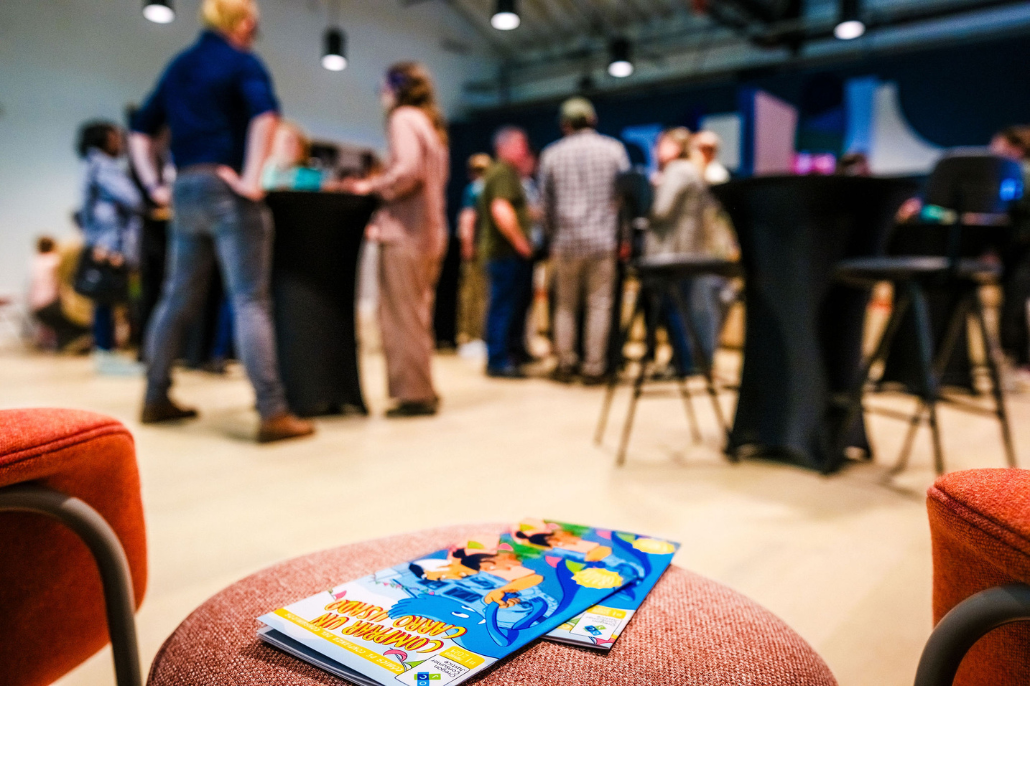 OCJ’s consumer comic books are in the foreground with launch party attendees out of focus in the background.