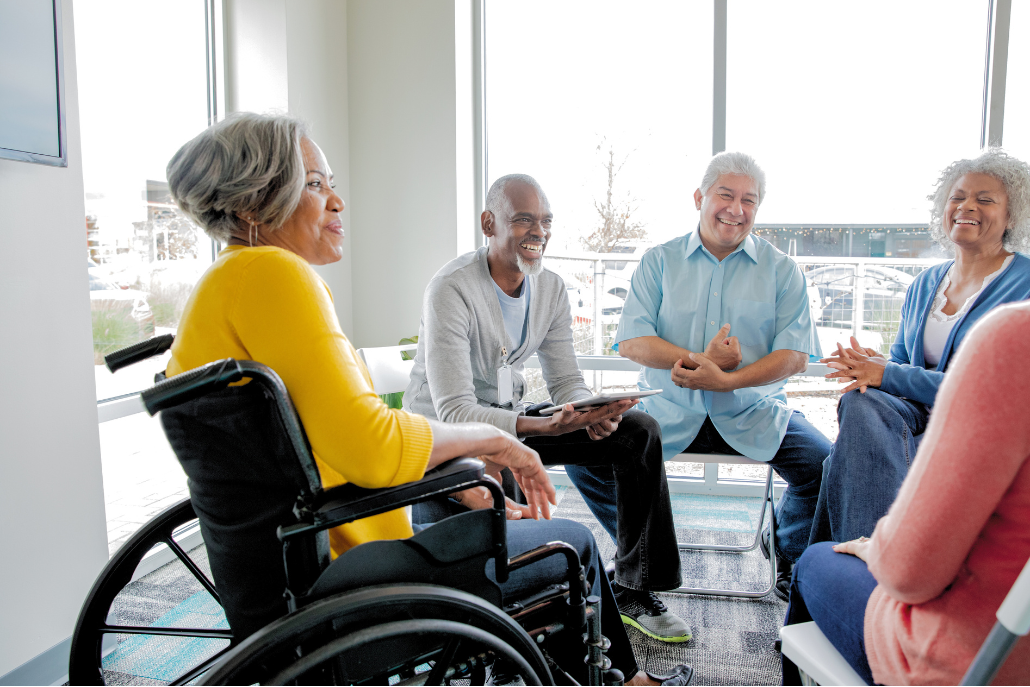 A group of older adults sitting on chairs in a circle. One woman is in a wheelchair.