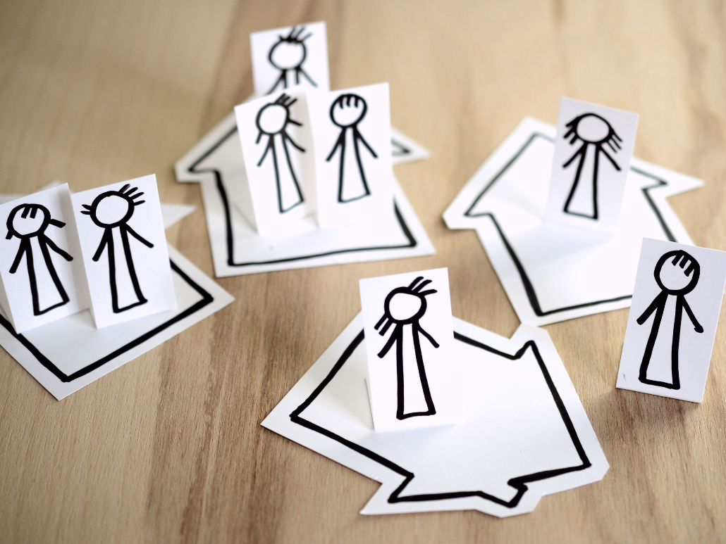 Drawings of stick figures representing differently aged people on several paper houses.