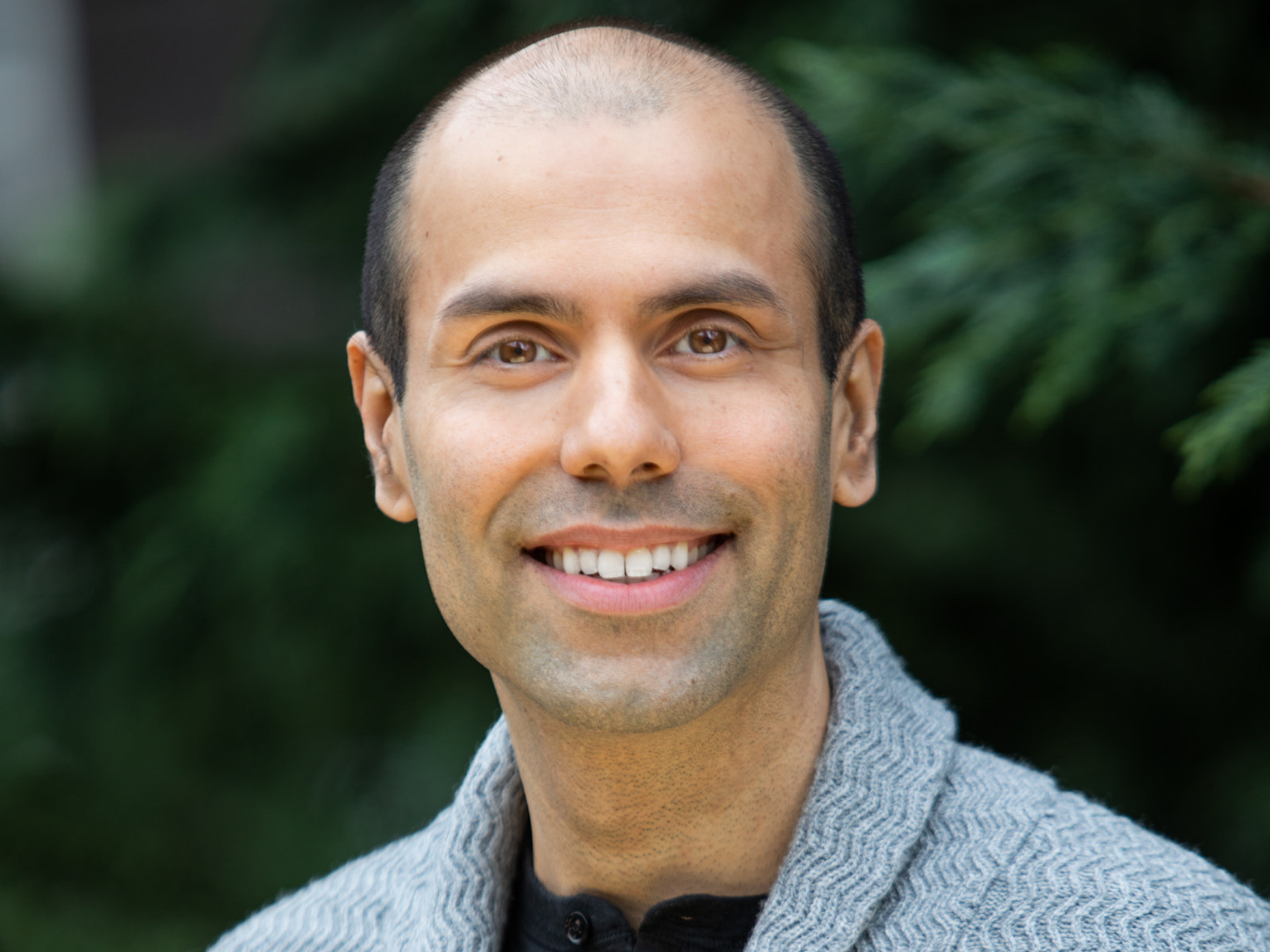 Portrait of executive director, Jagjit Nagra, smiling with short hair, wearing a gray sweater.