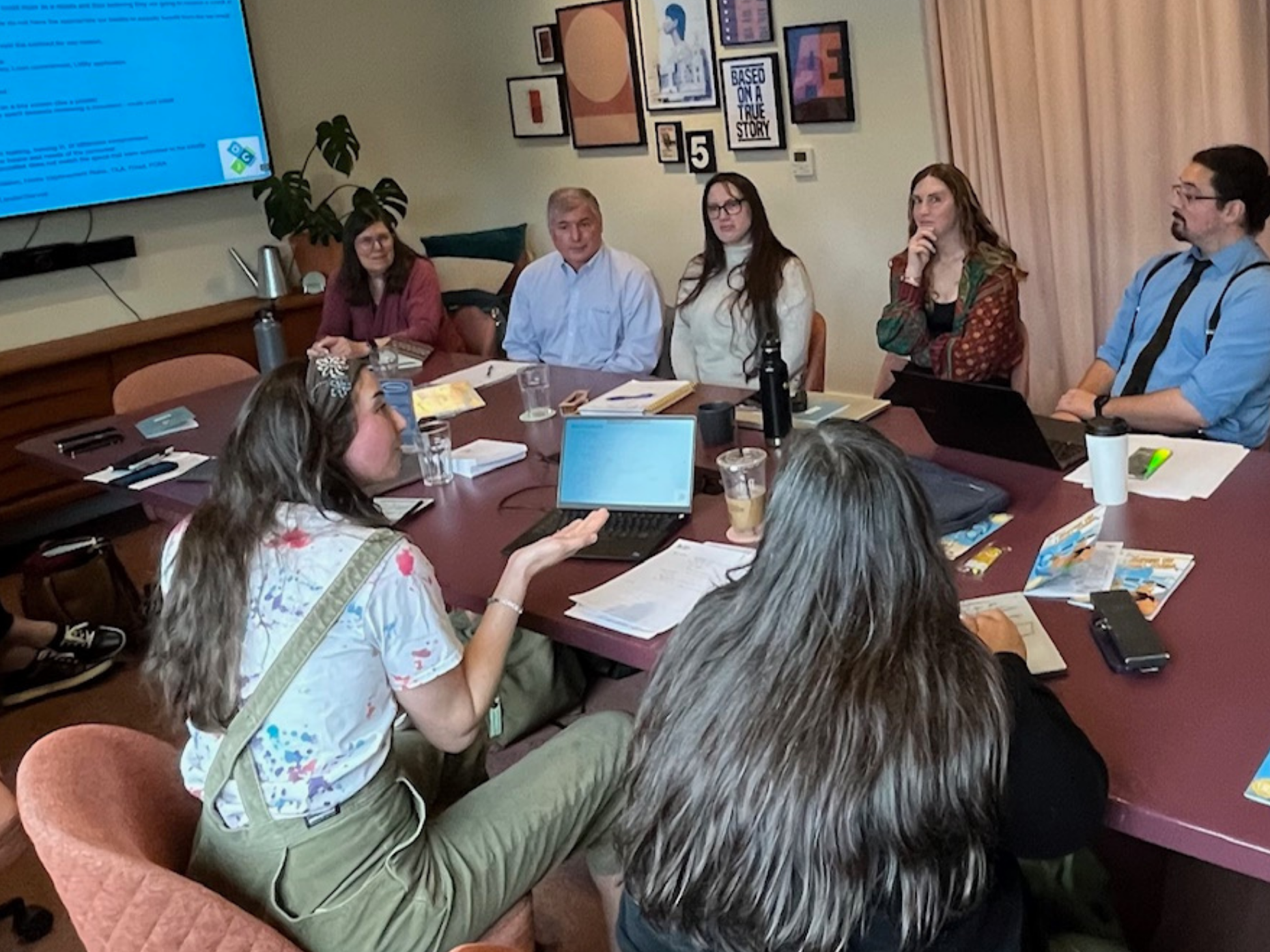 OCJ staff and interns gather in a conference room to hear final presentations. 