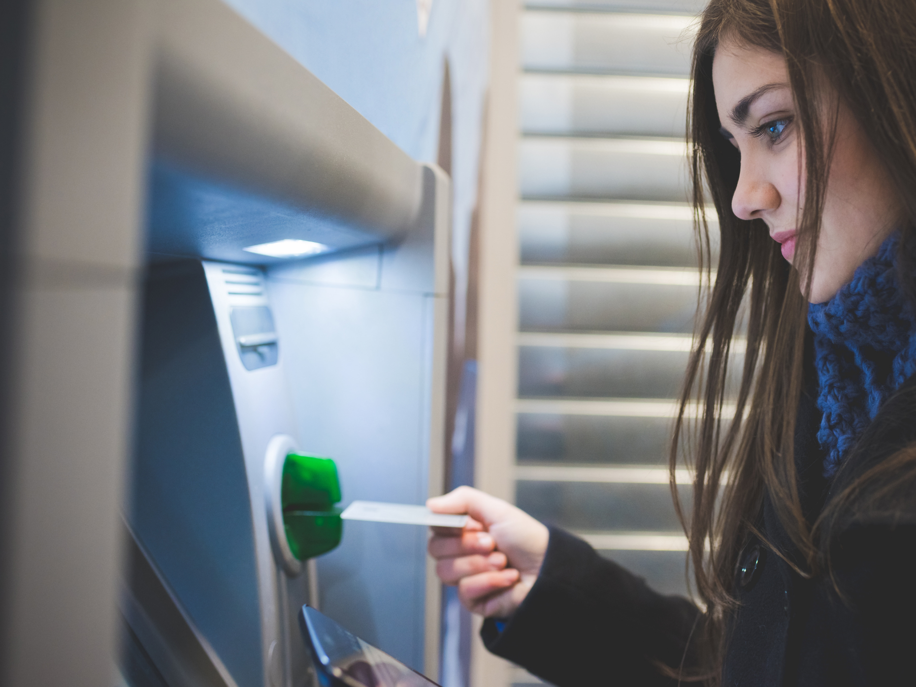 Young woman inserting a bank card into an ATM machine.