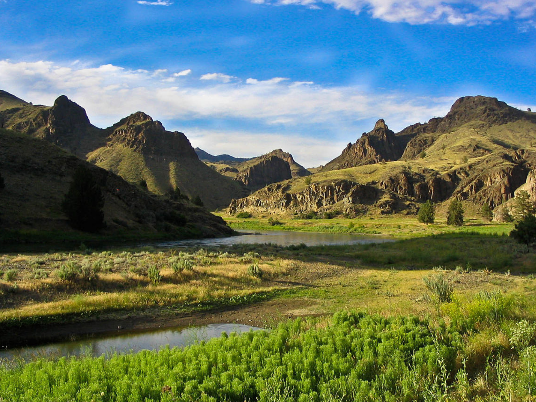 Scenic view of a river and hills under a blue sky.