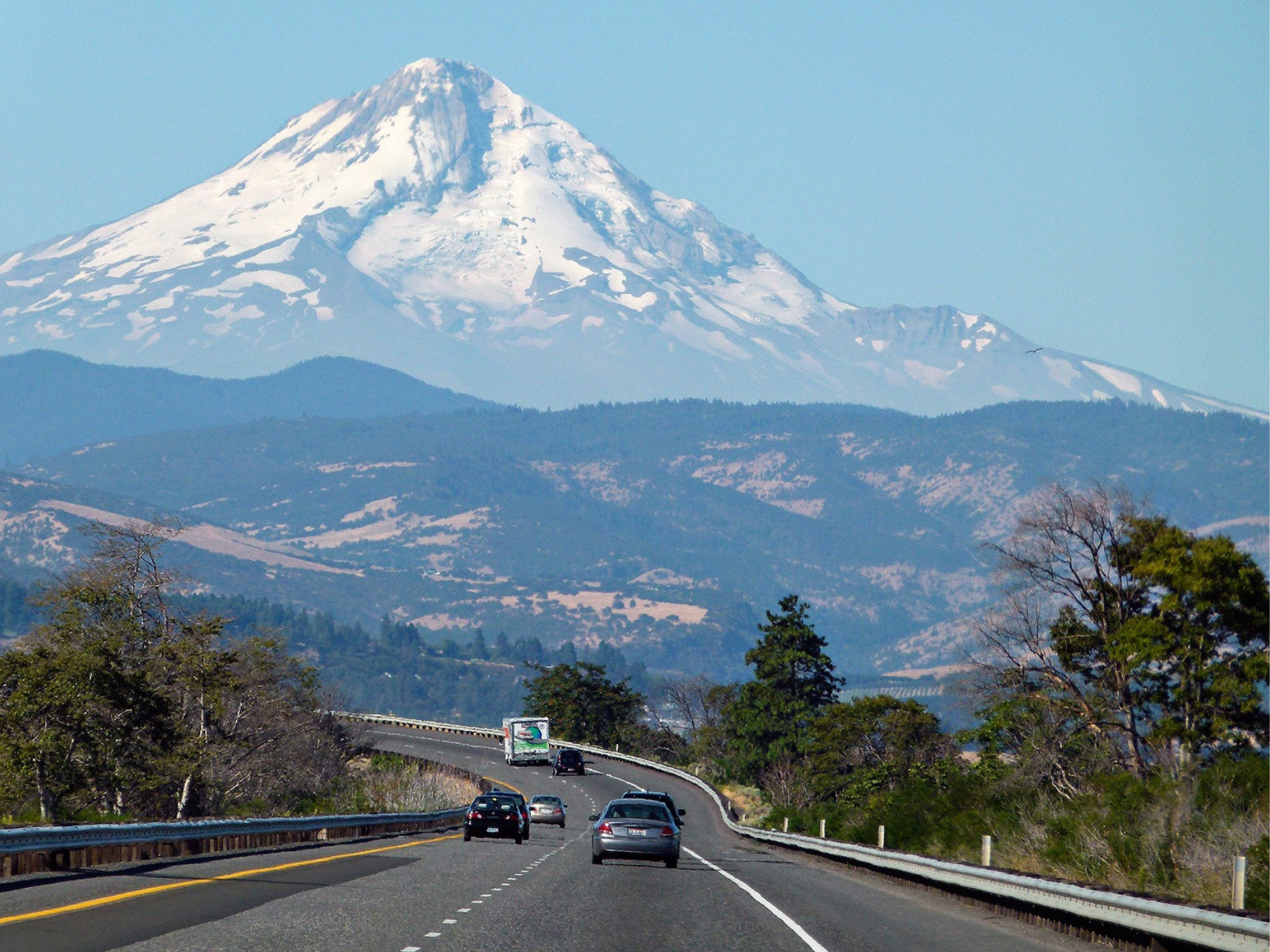 Cars driving on a highway with a snow-capped Mt. Hood in the background.