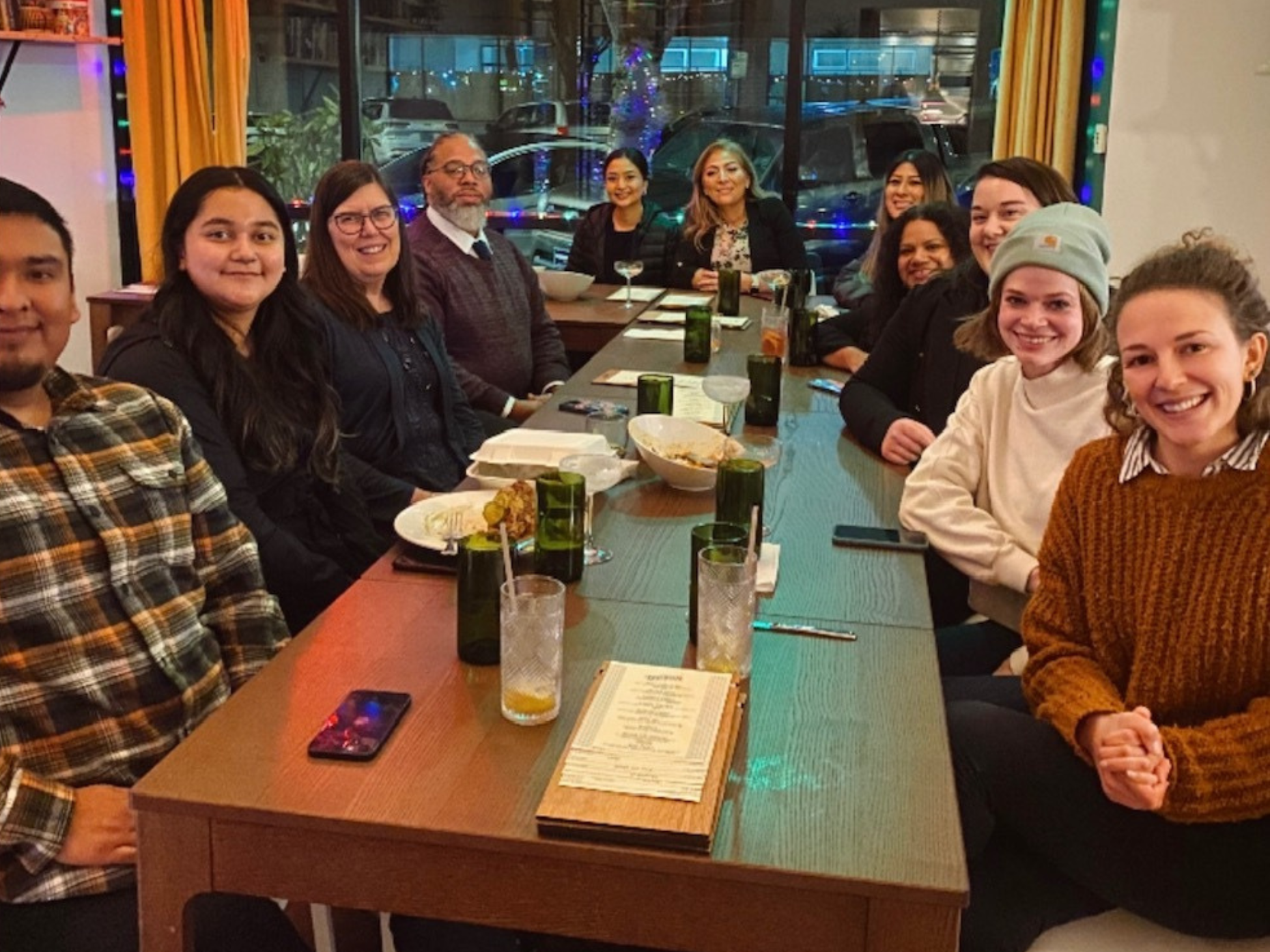 Policy cohort members and OCJ staff gathered around a dinner table, all looking and smiling at the camera.
