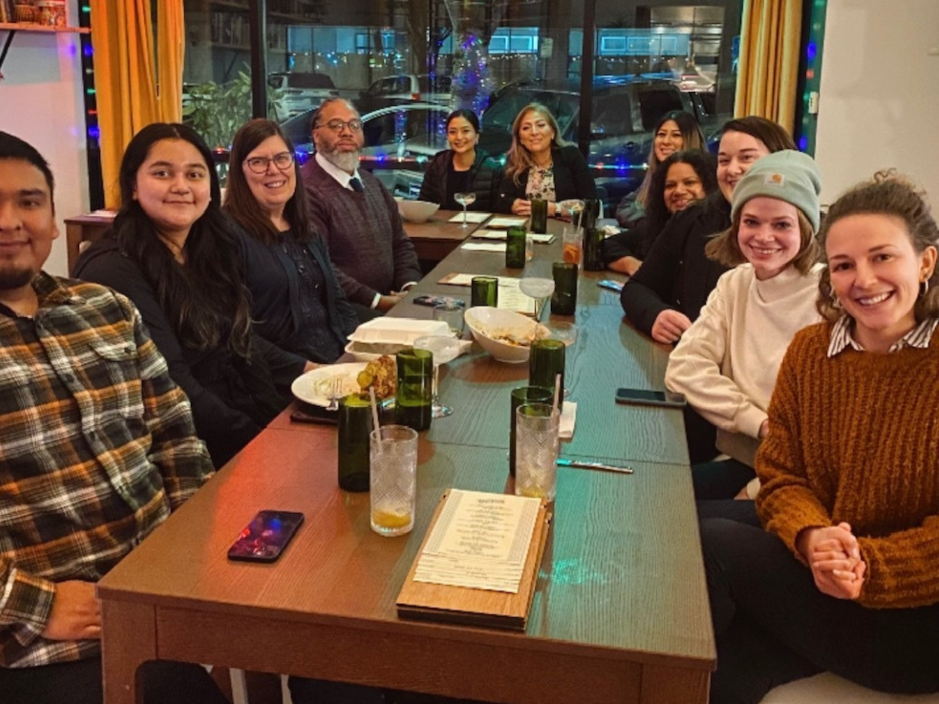 Policy cohort members and OCJ staff gathered around a dinner table, all looking and smiling at the camera. 