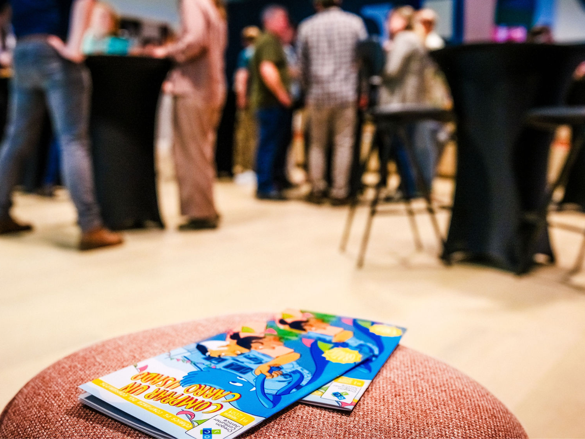 OCJ’s consumer comic books are in the foreground with launch party attendees out of focus in the background. 