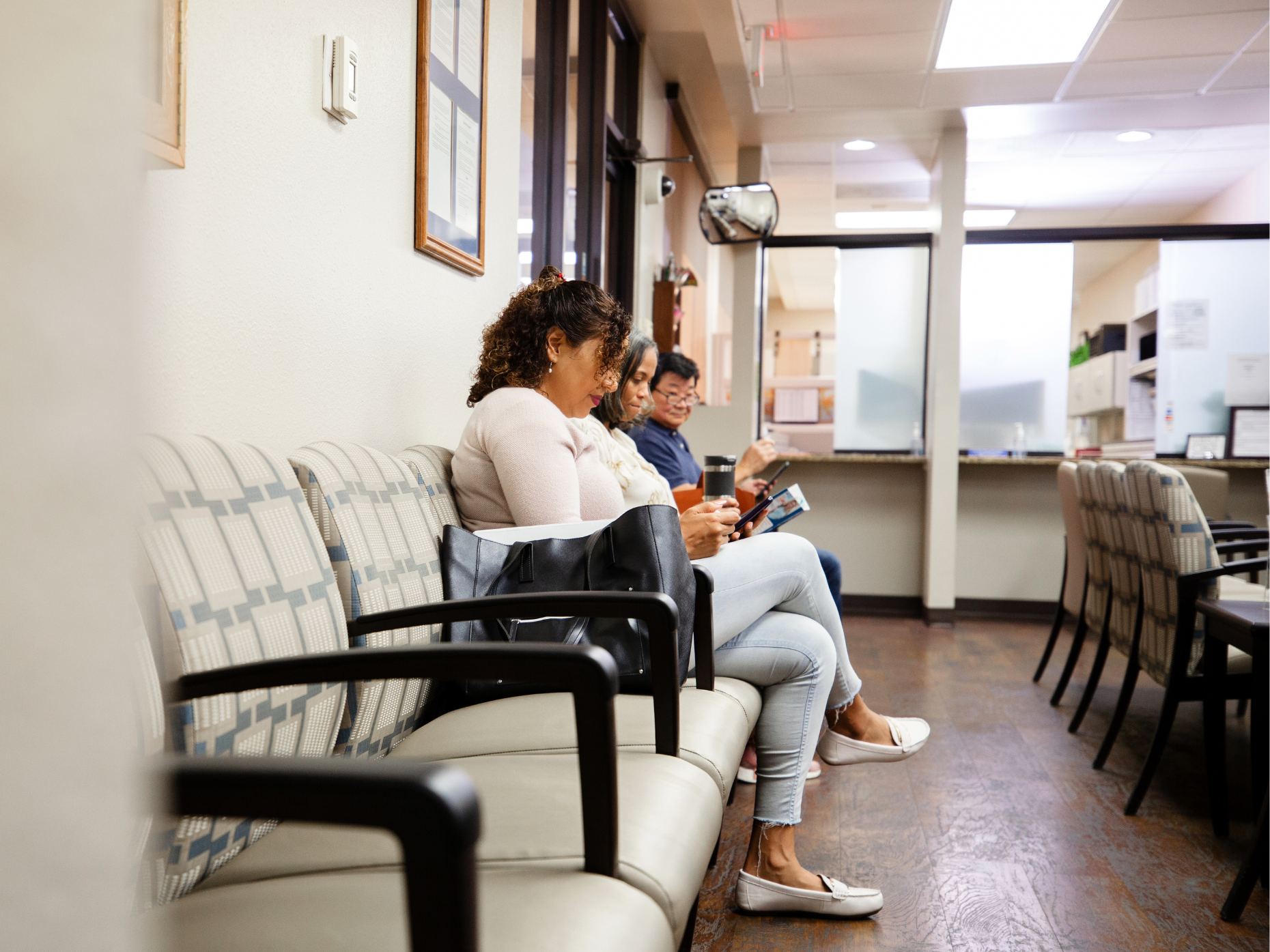 People sitting in chairs in the lobby of a doctor's office.