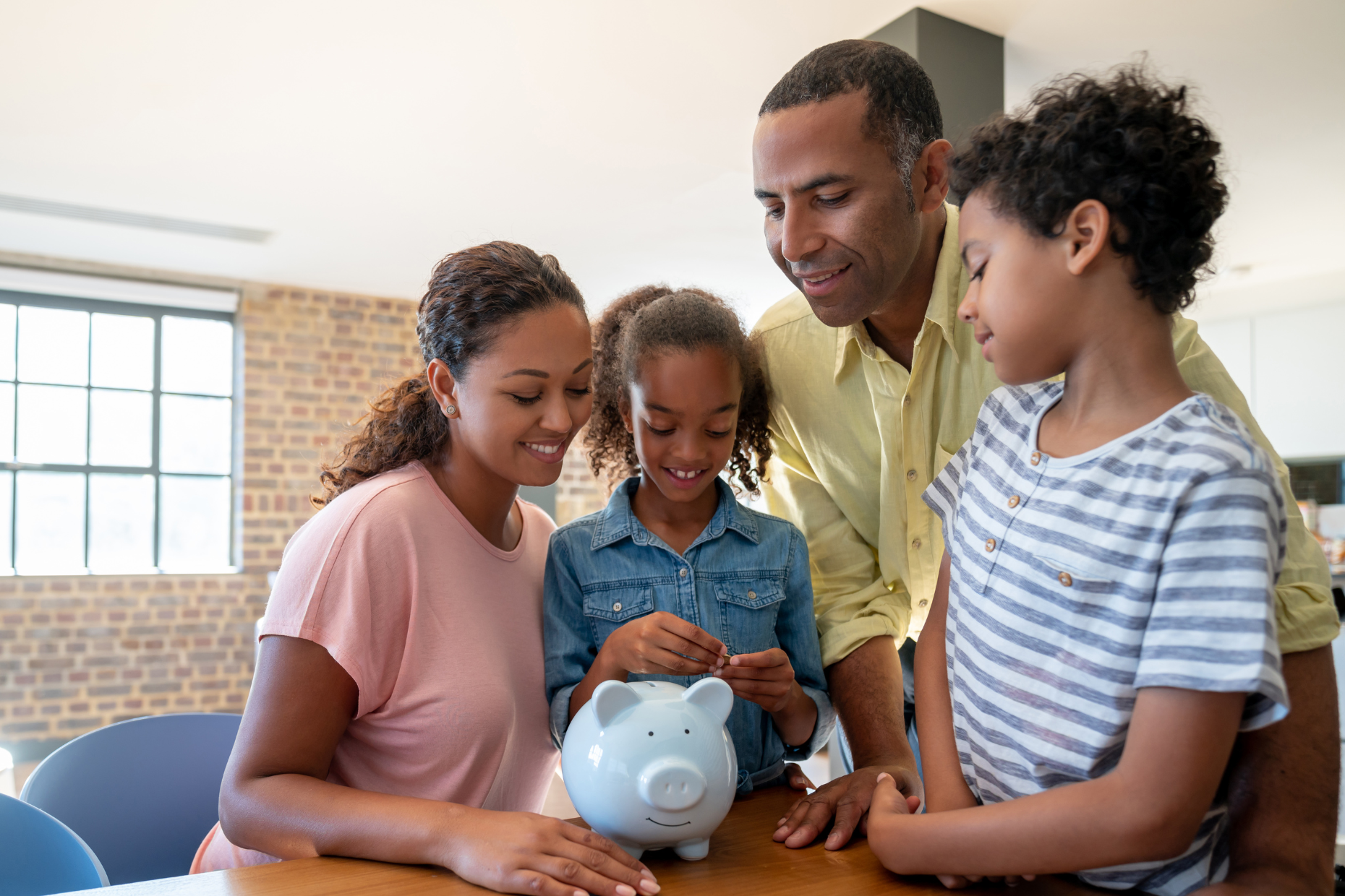 A family looking at a piggy bank in the kitchen.