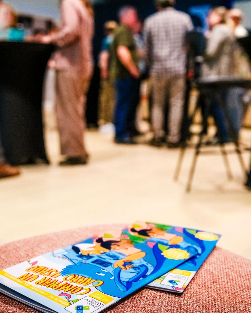 OCJ’s consumer comic books are in the foreground with launch party attendees out of focus in the background. 